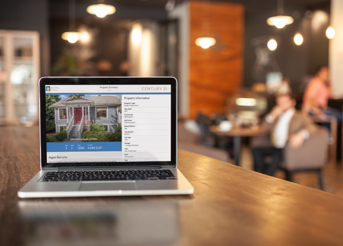 Real estate listing presentation displayed on a laptop in a coffee shop