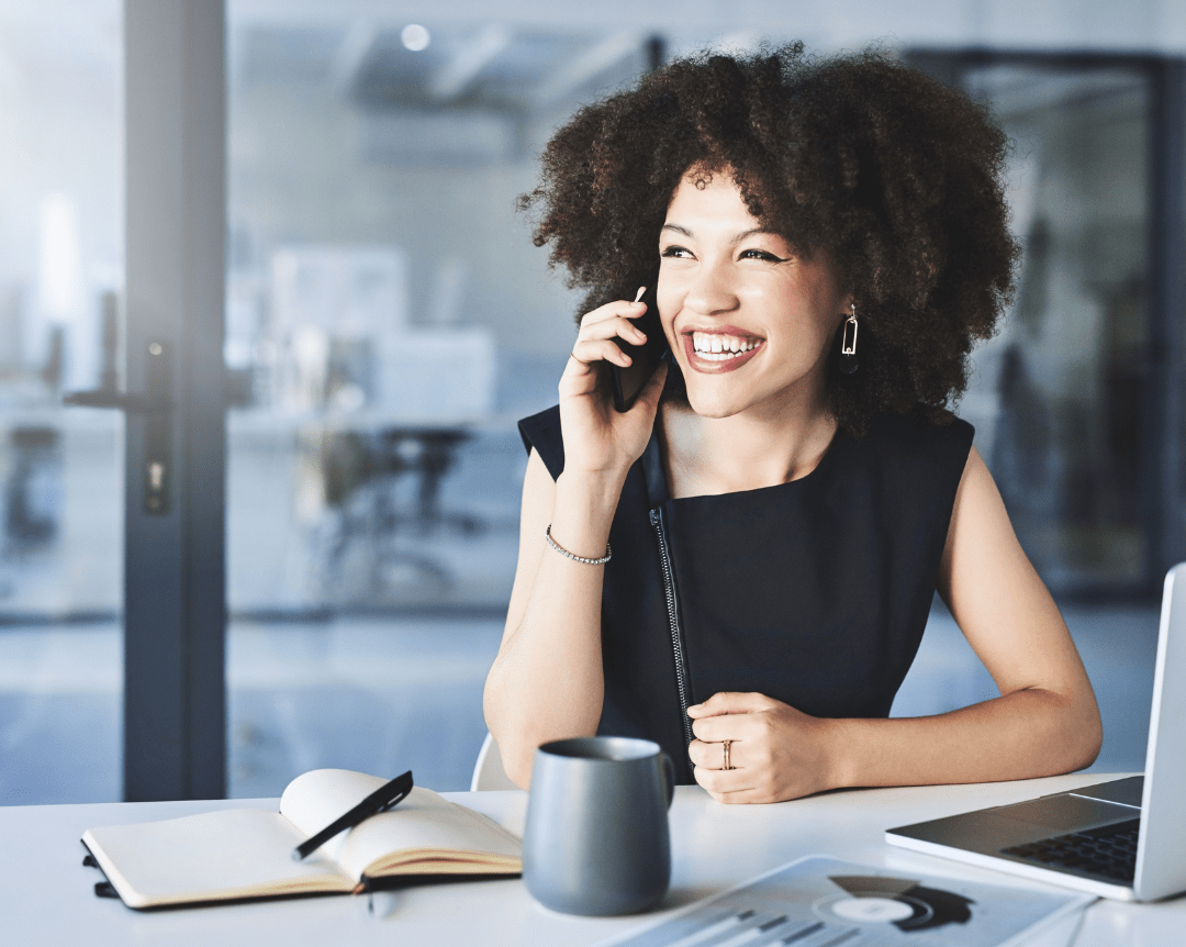 A real estate agent happily talking on the phone at her desk, representing CENTURY 21 Triangle Group's friendly and professional environment.