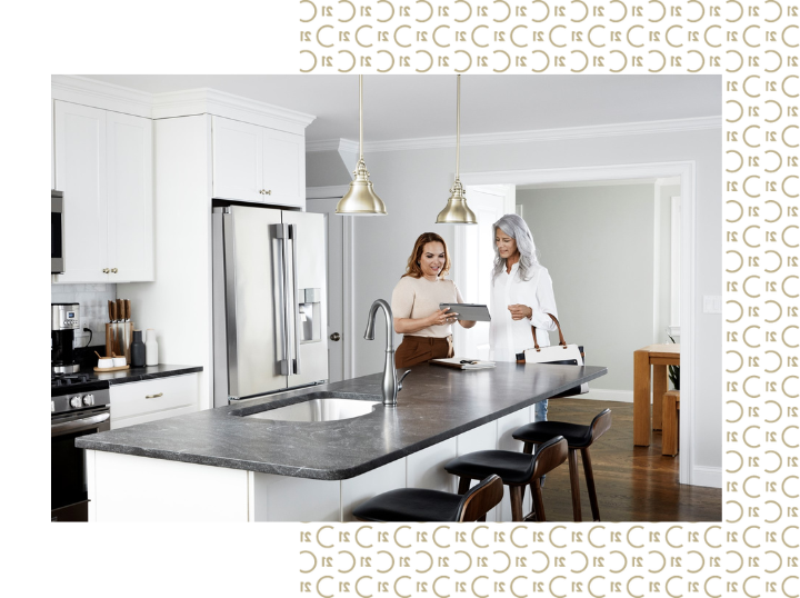 A Century 21 agent giving a consultation to a client in a modern kitchen.