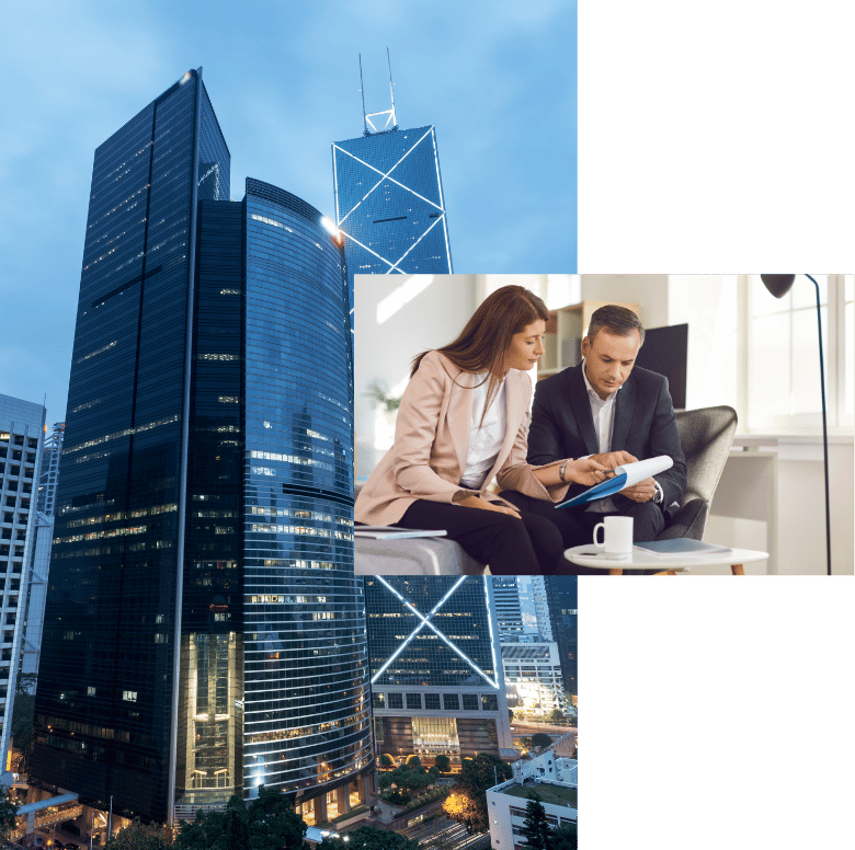 A professional man and woman reviewing documents in an office, with tall commercial buildings in the background.