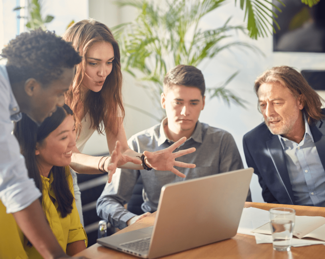 Diverse team of real estate professionals engaged in a collaborative mentorship session at CENTURY 21 Triangle Group office, discussing strategies around a laptop.